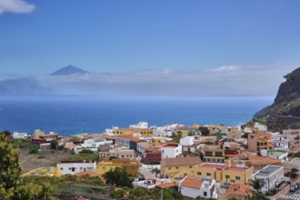 The village of Agulo, behind Tenerife and the Teide in clouds, Agulo, La Gomera, Canary Islands,