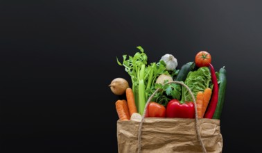 top view of fresh organic vegetables bought on weekly market in brown paper bag against dark table