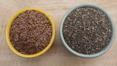 Chia Seeds (Salvia hispanica) vs Flaxseeds (linseeds) in Bowls on Wooden Background, Flat Lay Photo