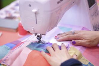 Sewing machine with hands of the seamstress at Creativeworld Frankfurt