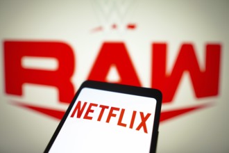 In this photo illustration, the Netflix logo is displayed on a smartphone screen and WWE Raw logo