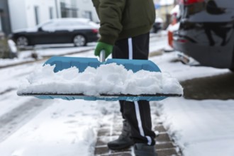 Child shoveling and removing snow in front of his house in the suburb