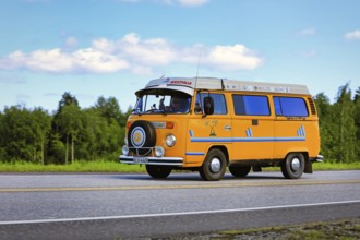Classic yellow Volkswagen Westfalia camper van at speed on Highway 2 on a beautiful day of summer.