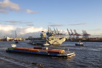 Freighter and aircraft carrier HMS Queen Elizabeth, warship of the British Royal Navy on the river