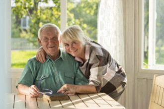 Senior couple with a book. Man and woman smiling indoor. Two lives, one story