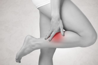 Female with pain in her lower leg, isolated in grey