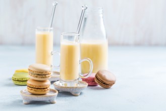 Assorted delicious French macarons with egg liqueur or eggnog on blue background