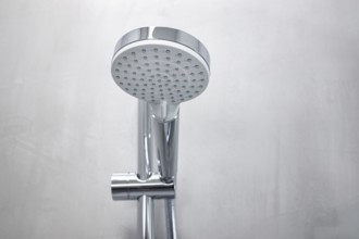 Shower head on a gray microcement wall of a modern bathroom