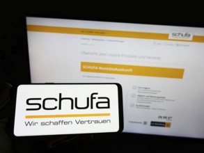 Stuttgart, Germany, 02-13-2022: Person holding mobile phone with logo of German credit protection