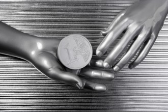Silver euro coins in futuristic robot gray metallic hands bank metaphor
