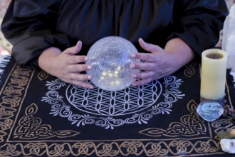 Close up of a woman fortune teller dressed in black reads the future in a crystal ball
