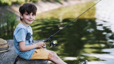 Portrait happy boy fishing lake