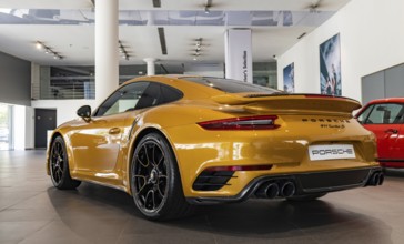 A picture of an orange Porsche 911 Turbo S inside a dealership