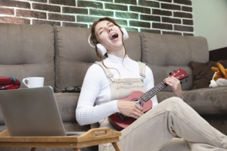 Remote music lessons, playing the ukulele or teaching vocals, singing. Hipster student recording