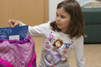 Child shows notebook from her first school bag, Austria, Europe