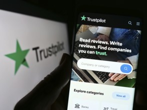 Stuttgart, Germany, 01-13-2023: Person holding cellphone with webpage of review platform company