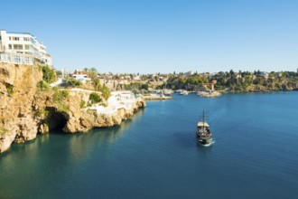 Tourist boat approaches the entrance to sea cave seen from Yavuz Ozcan Park with harbor in