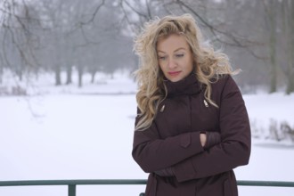 sad woman freezing in snow covered winter landscape
