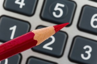 A red pen lies on a calculator. Saving on costs, expenditure and budget due to the poor economy