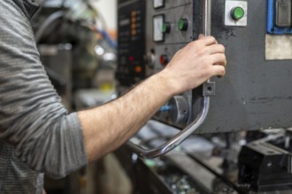Worker pressing buttons on CNC machine control board in factory. graphy