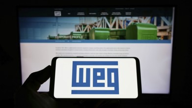 Stuttgart, Germany, 07-23-2022: Person holding mobile phone with logo of Brazilian company WEG