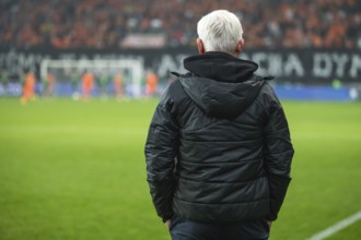 Head coach's back and soccer match at the stadium in the background