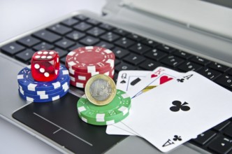 Playing cards, casino chips and Euro coin on a laptop keyboard symbolizing online gambling