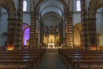 Interior view of an old church with imposing vaults and a central altar, surrounded by pews and