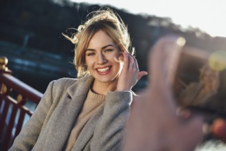 A man make a portrait of happy smiling woman standing on the bridge on sunny summer or spring day