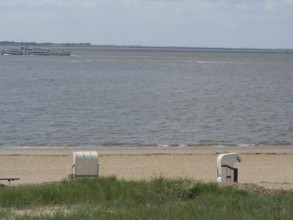 Two beach chairs on the beach with a view of the sea and a slightly cloudy sky, bremerhaven,