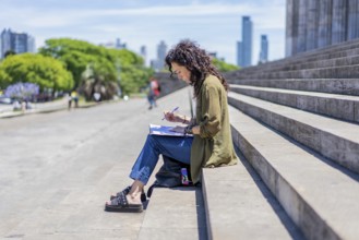 Thoughtful woman sketching on the steps of her college