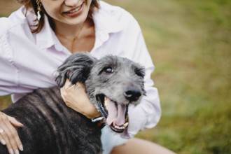 Close-up of a smiling woman with a happy dog outdoors on grass