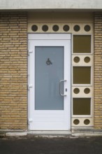 Public restroom door with accessibility sign for disabled people featuring frosted glass and white