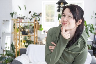 Thoughtful emotions of a woman in her home in a bright modern interior with home plants. Portrait