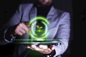 Businessman pointing to his cell phone with an icon of growing and protecting plants and the