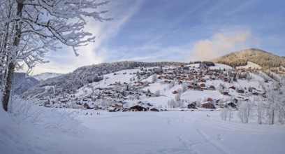 Winter panorama of snow covered La Clusaz village nestled in a hilly landscape in Annecy, France.