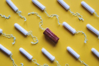 many new clean tampons and one used bloody tampon - period or menstruation flat lay concept with