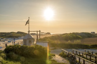 Beach access in the dunes with map house and bicycle stands backlit by the evening sun, St. Peter