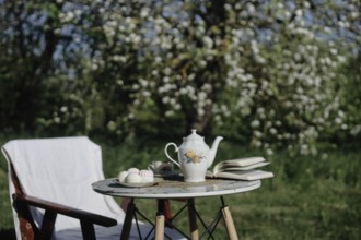 Outdoor table set with a teapot in a blossoming garden conveying a serene spring vibe
