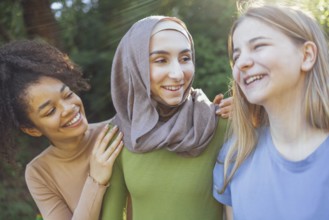 Multiracial young teen female friends walking in the park laughing and having fun together.