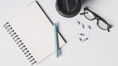 Blank spiral notepad pen coffee cup eyeglasses pushpins white background. Resolution and high