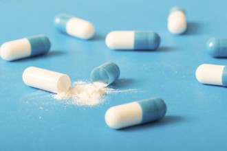 Broken white antibiotic capsule blue background