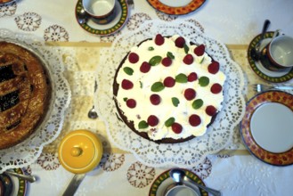 A raspberry cream cake beside a Linzer torte on a table before coffee and cake. Coburg, Germany,
