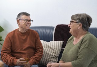 Happy retired couple enjoying a relaxing afternoon at home, sharing stories and drinks on a