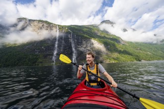 Kayak trip on the Geirangerfjord at the waterfall The Seven Sisters, Young man paddling in a kayak,