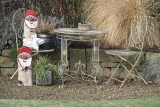 Iron garden furniture and Christmas gnome decorations on a gravel path, borken, North