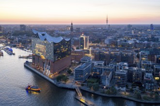 Aerial view of the Elbphilharmonie at sunset with illuminated windows and view over Hamburg,