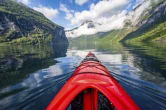 Kayak trip on the Geirangerfjord, tip of a red kayak in the fjord with reflection, atmospheric