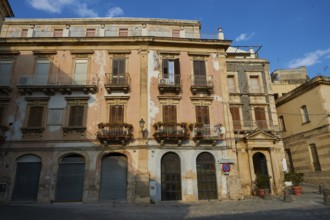 Historic building with worn balconies and shutters on a quiet street, Ortigia Island, Isola di