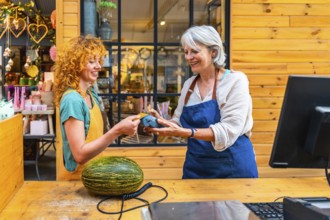 Happy customer paying with contactless credit card for a melon at a flower shop counter, small
